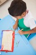 © WavebreakMediaMicro - Cute little boy painting at table in classroom
