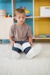 © WavebreakMediaMicro - Cute little boy sitting on floor reading in classroom