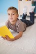 © WavebreakMediaMicro - Cute little boy sitting on floor reading in classroom