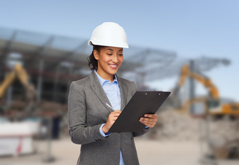 Poster - smiling businesswoman in helmet with clipboard