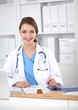 © lenets_tan - Beautiful young smiling female doctor sitting at the desk and