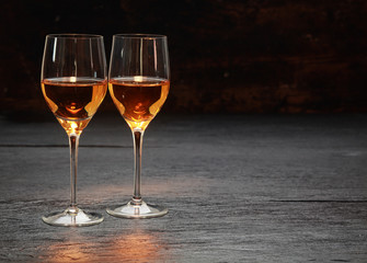 two wine glasses standing on stone surface