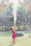Fototapeta Tęcza - Dziewczynka w różowej sukience oblewająca się wodą