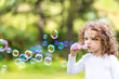 © ulkas - A little girl blowing soap bubbles, closeup portrait beautiful c