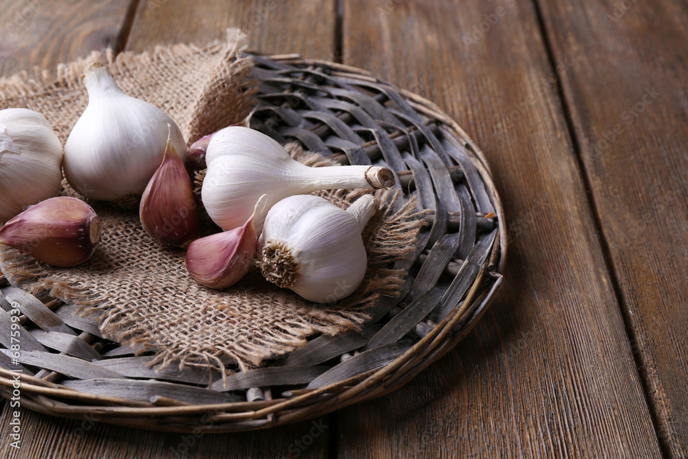 Fresh garlic on wicker mat, on wooden background