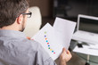 © BlueSkyImages - young man looking at paper in glasses.