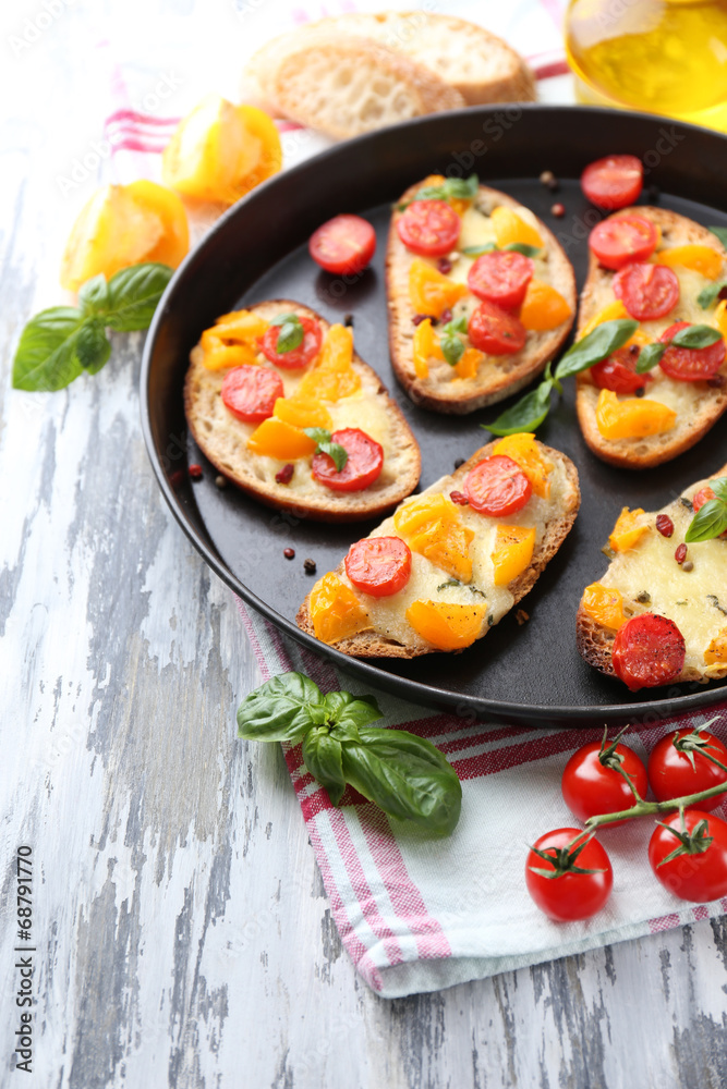 Tasty bruschetta with tomatoes on pan, on old wooden table