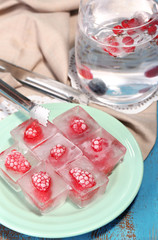 Wall Mural - Ice cubes with raspberry on plate, on color wooden background