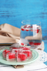 Wall Mural - Ice cubes with raspberry on plate, on color wooden background