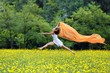 Agile woman leaping in the air trailing a scarf