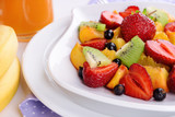 Fototapeta  - Fresh fruits salad on plate on napkin close up