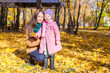 © travnikovstudio - Little cute girl and happy mother in yellow autumn park