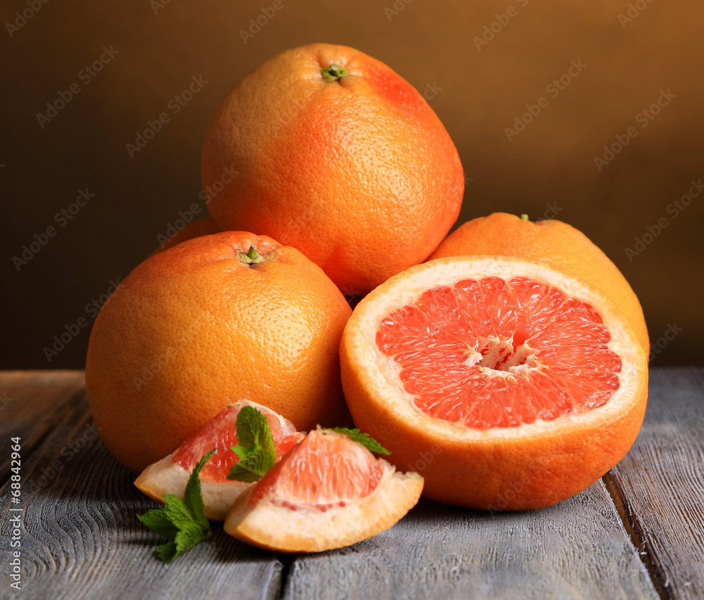 Ripe grapefruits on wooden board, on dark color background
