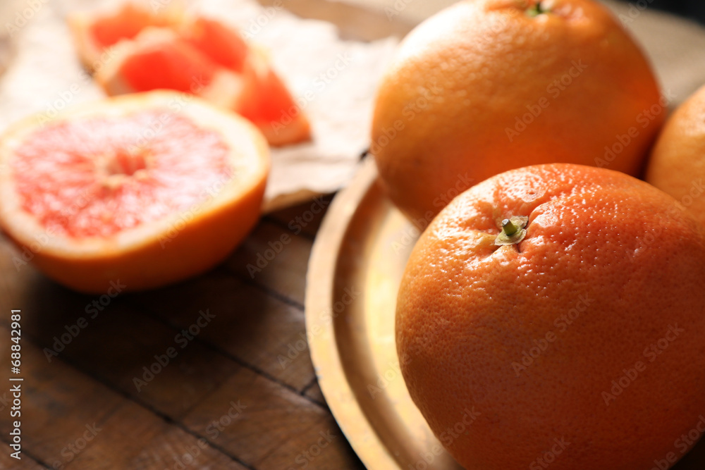 Ripe grapefruits on cutting board, on wooden background