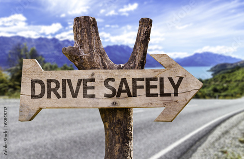 Fotografie, Obraz Drive Safely wooden sign with a street background