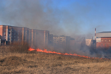 Fire burns grass field brick houses