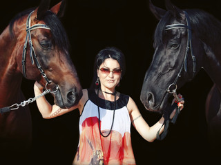 young girl in dress with  two horses at black background