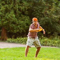 man playing in the park with a plate frisbee