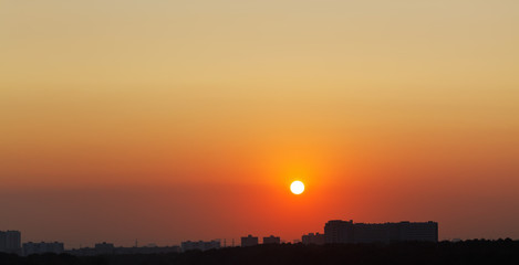 Wall Mural - sun in red sky over city at sunrise