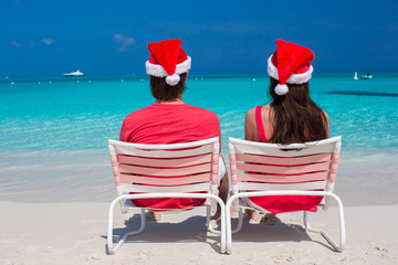 Wall Mural - Happy romantic couple in red Santa Hats at tropical beach