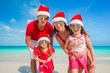 © travnikovstudio - Portrait of happy family in Santa hats on the beach