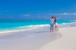 © travnikovstudio - Young happy couple in red Santa hats on tropical beach
