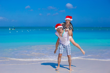 Sticker - Young happy couple in red Santa hats during their tropical