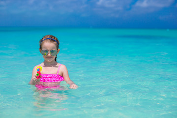 Sticker - Happy little girl playing with toys during caribbean vacation