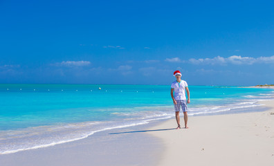 Wall Mural - Young man in santa hat during beach vacation