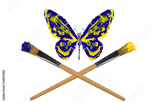 Fotografie, Obraz Yellow and blue painted butterfly hover above crossed paintbrush