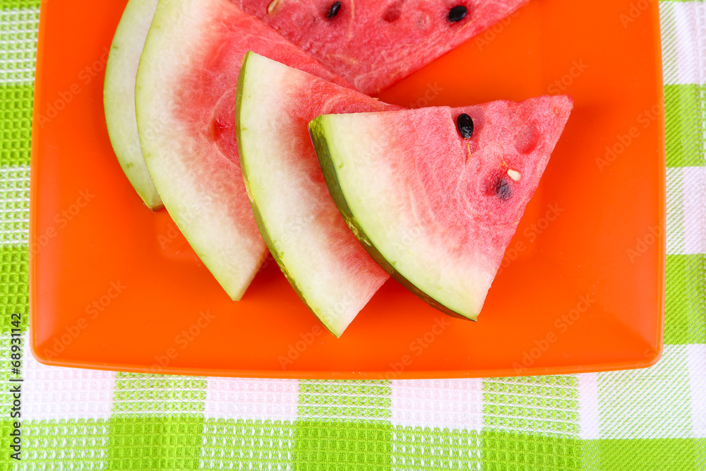 Watermelon on orange plate on  green tablecloth