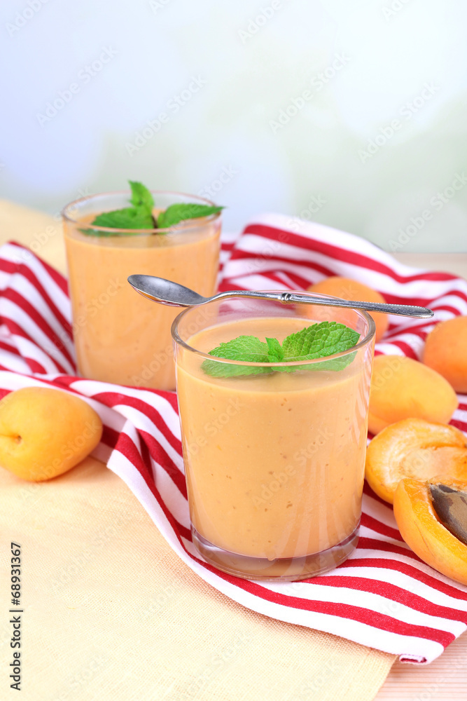 Apricot dessert in glasses on table on bright background