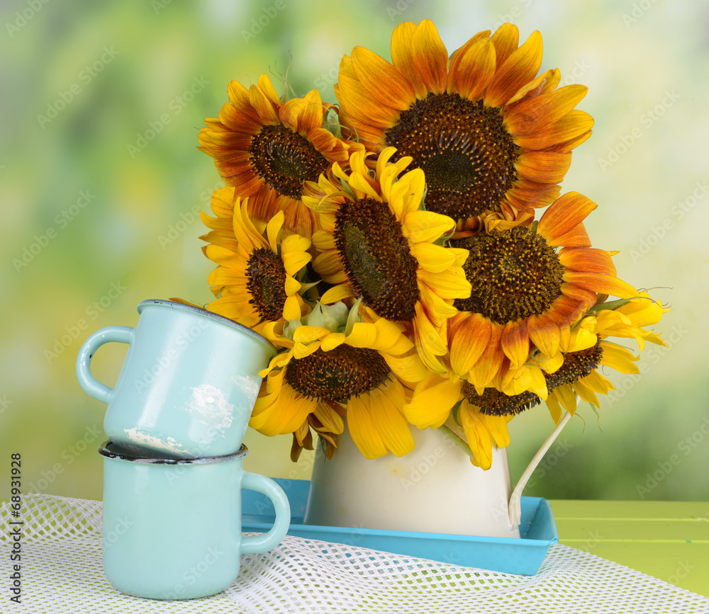 Beautiful sunflowers in pitcher with mugs