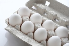 White chicken raw eggs in a box on a white