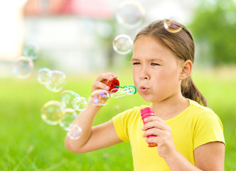 Wall Mural - Little girl is blowing a soap bubbles