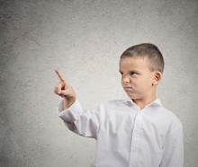 Unhappy Boy Pointing With Finger At Copy Space, Grey Wall