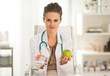 © Alliance - Doctor woman showing apple and pack of money