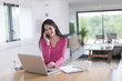 © jackfrog - attractive woman at phone works on her laptop at home