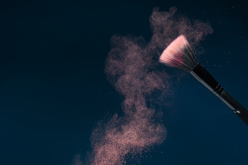 professional black make-up brush with pink powder in motion isol