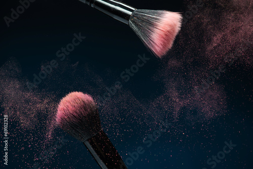 Fotografía Professional black make-up brush with pink powder in motion isol
