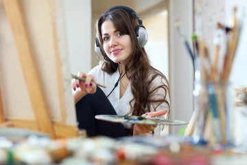 Wall Mural -  girl in headphones  paints with oil colors