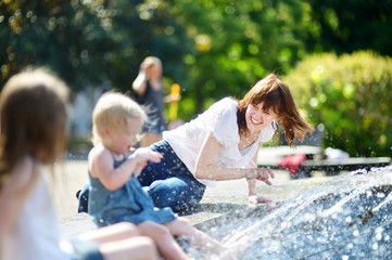 Young woman and two kids by a city fountain