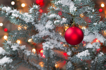 Snow covered Christmas tree with hanging Red Ornament