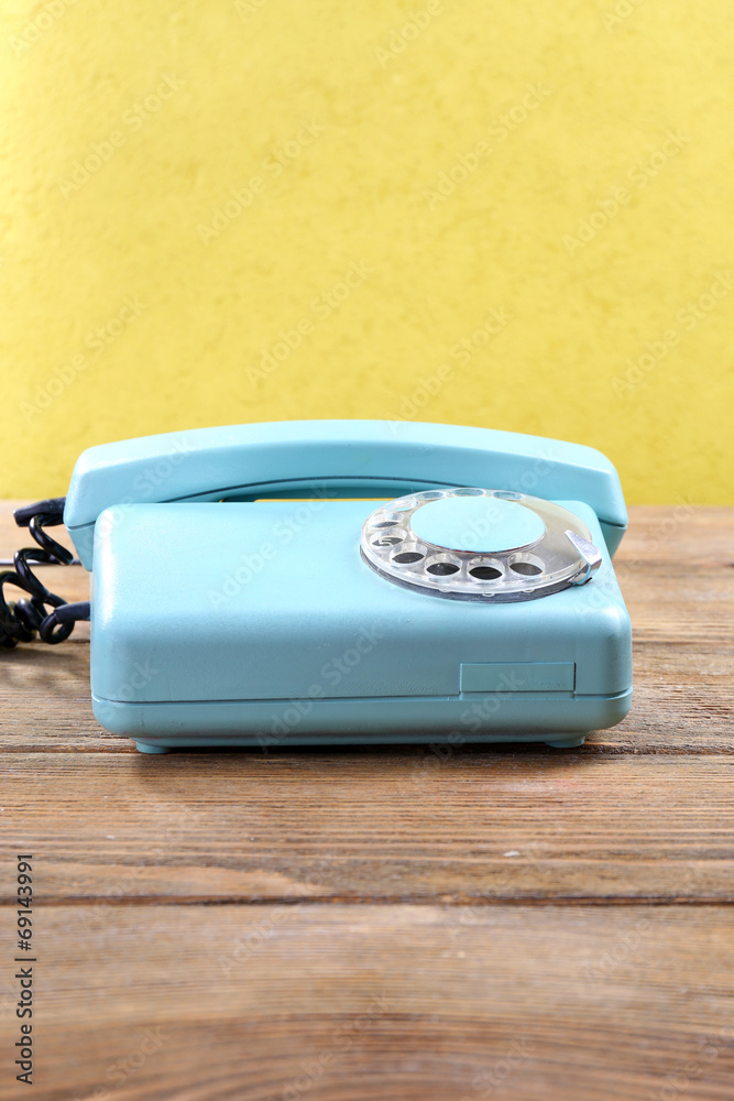 Retro turquoise telephone on wooden table, on color background