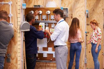 Teacher Helping Students Training To Be Electricians