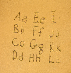 Wall Mural - Alphabet written on a sand beach. (A-L)