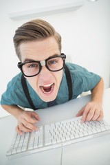 Poster - Casual angry businessman typing at his desk