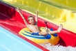 Funny child riding on float in water park splashing water 