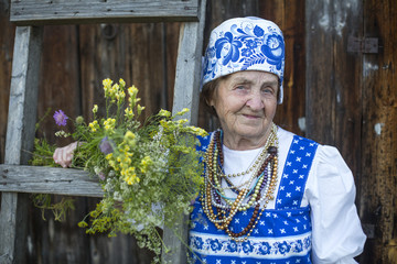 Old woman in russian ethnic clothes, outdoors.