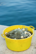 Gray Fishing Net On The Heap In The Yellow Plastic Container